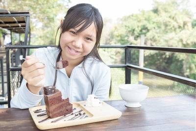 Portrait of smiling woman holding ice cream on table