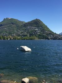 Scenic view of sea and mountains against clear blue sky
