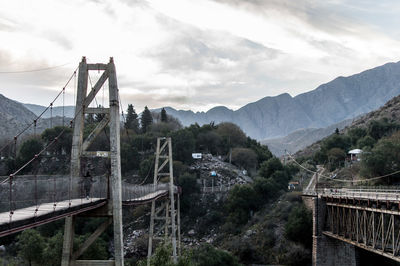 Bridge by mountains against sky