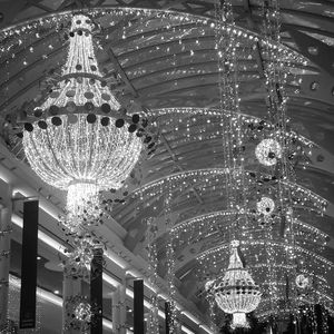 Low angle view of illuminated lighting equipment hanging at night