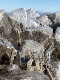 Water flowing through rocks against sky during winter