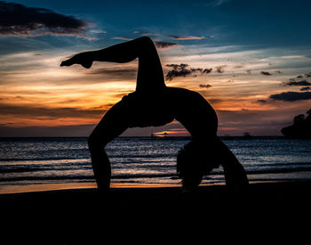 Silhouette people on beach against sky during sunset