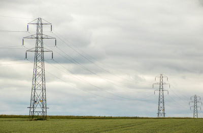 Low angle view of electricity pylon on field against sky