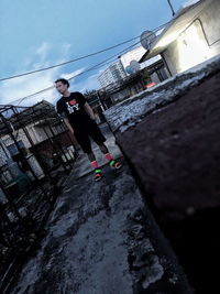 Man standing by building against sky