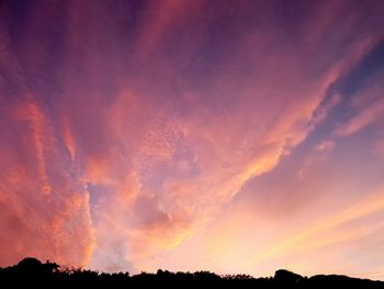 Low angle view of silhouette trees against dramatic sky