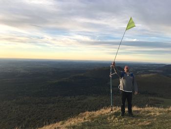 Man waving flag on mountain against sky