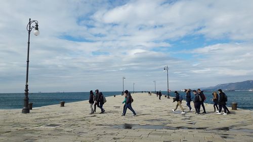 People on pier over sea against sky