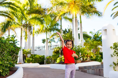 Portrait of young woman standing against palm trees