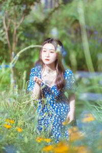 Portrait of young woman standing amidst plants