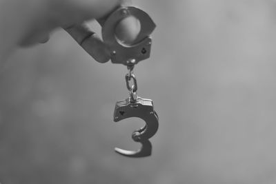 Close-up of hand holding chain hanging from metal