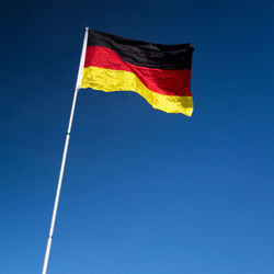 Low angle view of flag against blue sky