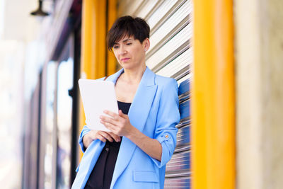 Portrait of smiling young businesswoman standing against building