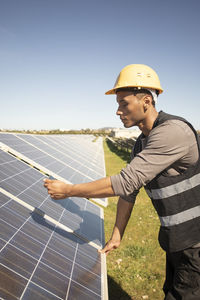 Young male maintenance engineer photographing solar panels through smart phone at power station