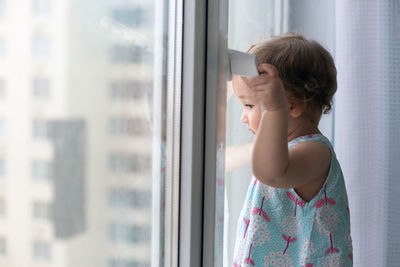 Boy looking through window at home