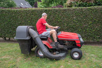 Lawn mower mows the grass, a middle-aged male gardener works on a mini tractor