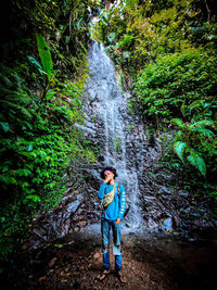 Man standing by waterfall in forest