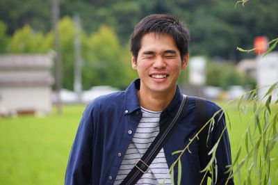 Young man smiling while standing with eyes closed at park