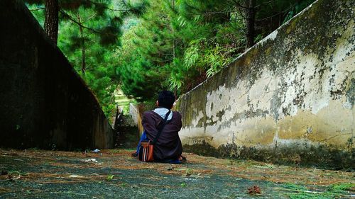 Rear view of man sitting on footpath