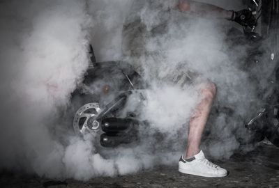 Low section of man standing on smoke emitting