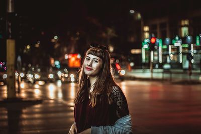 Portrait of woman standing in illuminated city at night