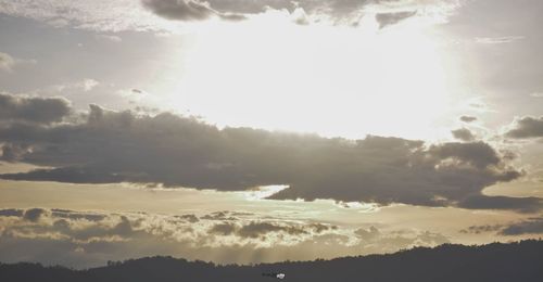 Low angle view of sunlight streaming through clouds