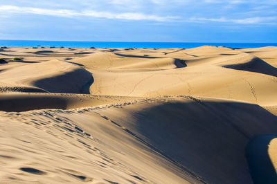 Scenic view of sand dunes against sky