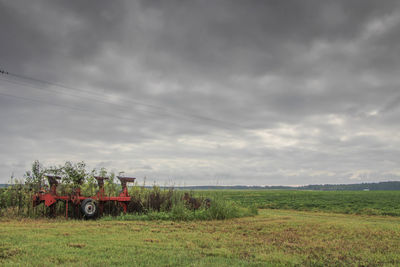 Scenic view of grassy field against cloudy sky