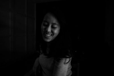 Portrait of smiling woman standing against black background