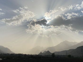 Sunlight streaming through clouds over landscape