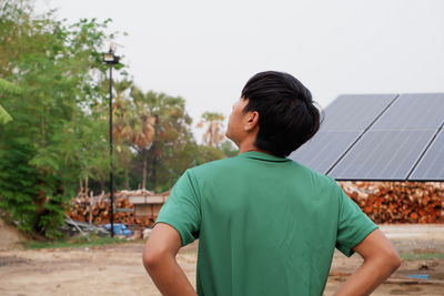 Rear view of boy standing against sky