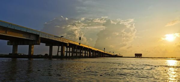 Bridge over sea against sky during sunset