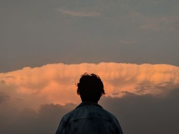 Rear view of man standing against sky during sunset