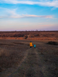 Travelers father daughter walking together on hill scenic landscape sunset sky hiking trail journey