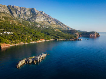 Scenic view of sea and mountains against blue sky