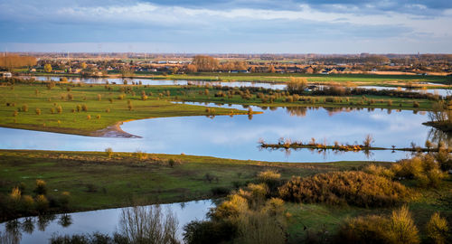 Scenic view of lake by field against sky