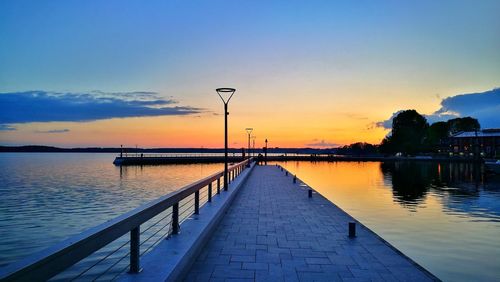 Pier over lake against sky during sunset