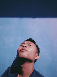 Close-up of man looking up standing by wall