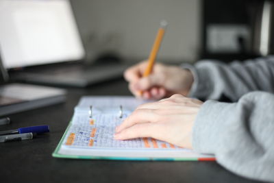 Midsection of boy holding pencils on table