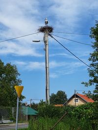 Low angle view of telephone pole by building against sky