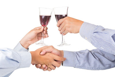 Midsection of couple holding glass against white background