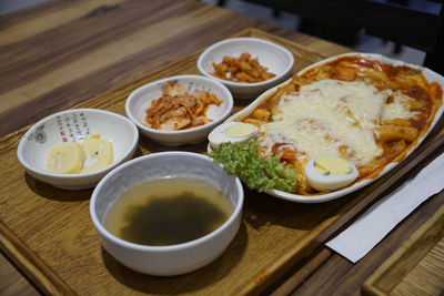 Cheesy tteokbokki served with kimchi and side dishes