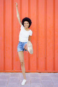 Full length of woman standing against yellow wall