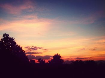 Silhouette trees against dramatic sky during sunset