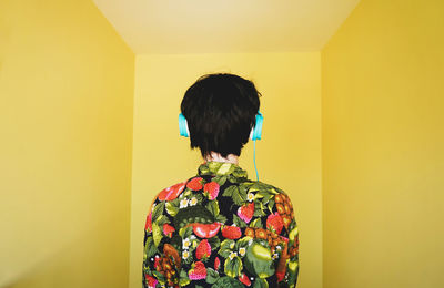 Rear view of woman against yellow background