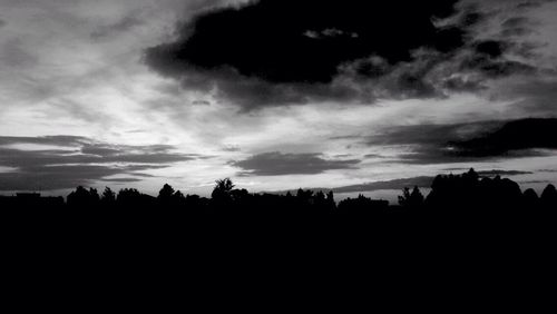 Silhouette landscape against cloudy sky