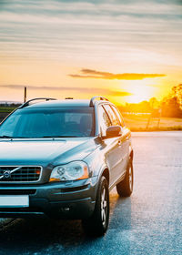 Cars on road against sky during sunset