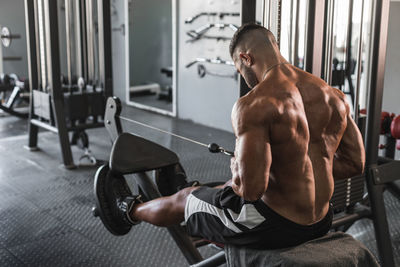 Side view of shirtless young man looking at camera