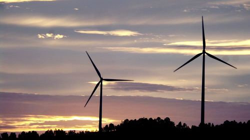 Low angle view of wind turbine against sky during sunset