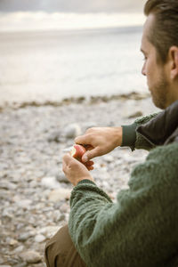 Cropped image of man cutting apple at beach