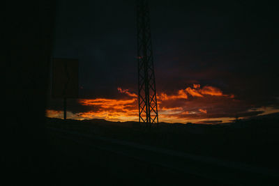 Silhouette electricity pylon against sky during sunset